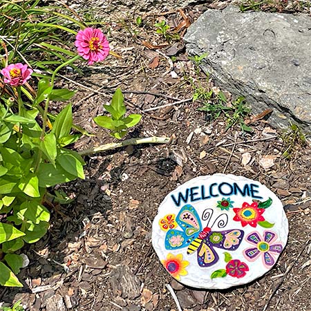 round resin stepping stone with a vibrant butterfly design, surrounded by flowers with the word "Welcome"